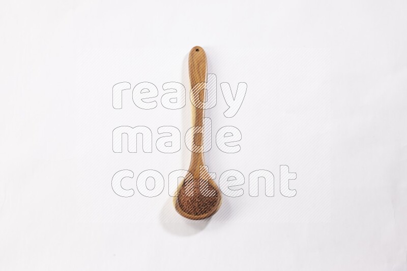 A wooden ladle full of garden cress seeds on a white flooring