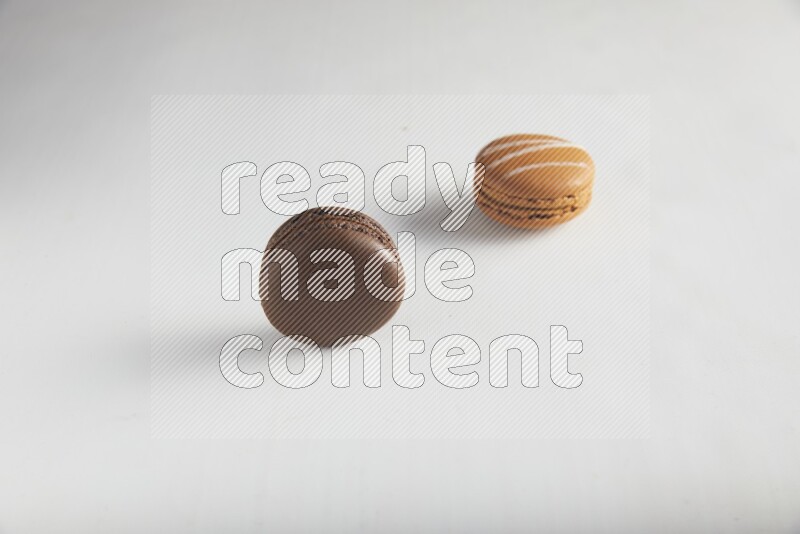 45º Shot of of two assorted Brown Irish Cream, and Brown Dark Chocolate macarons on white background