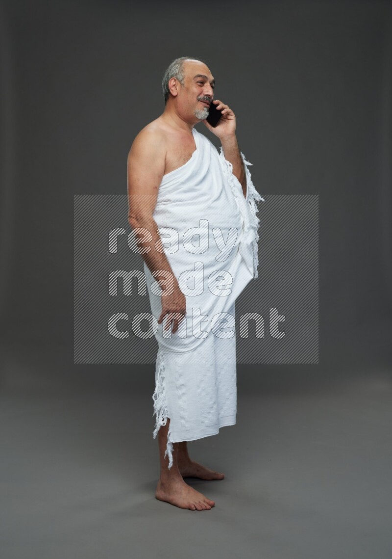 A man wearing Ehram Standing talking on phone on gray background