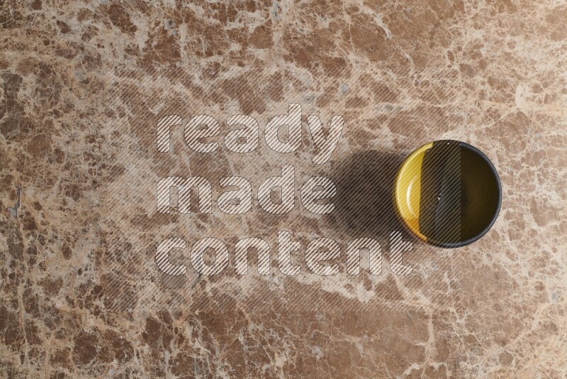 A multicolored pottery bowl on beige marble background