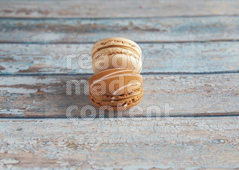 45º Shot of of two assorted Brown Irish Cream, and White Caramel fleur de sel macarons on light blue background