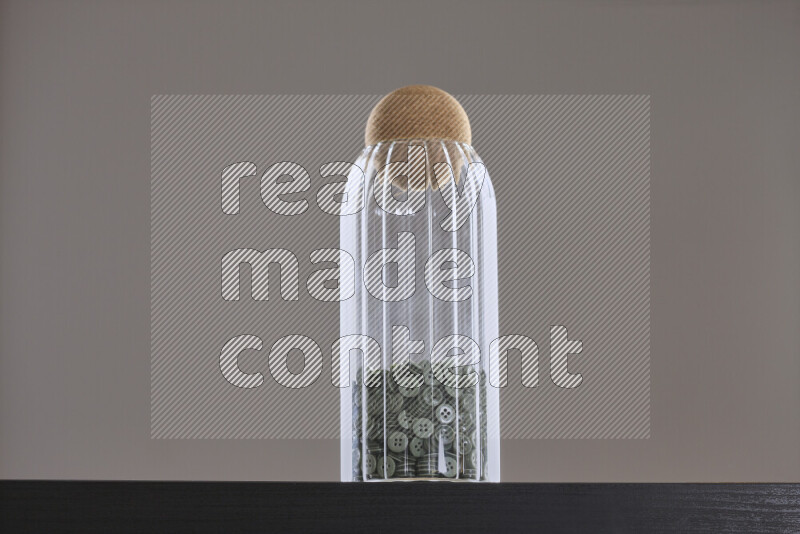 أزرار متنوعة في وعاء زجاجي علي خلفية سوداء