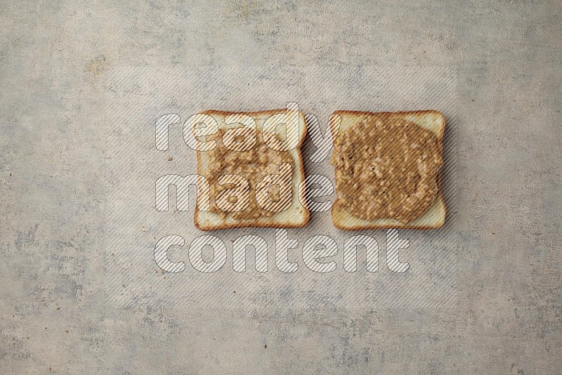 Crunchy peanut butter on a toasted white toast slices on a light blue textured background