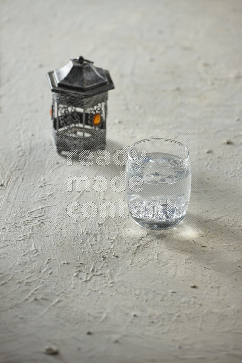 فانوس فضي مع مشروبات مختلفة وتمر ومكسرات وسبحة صلاة وقرآن على خلفية بيضاء