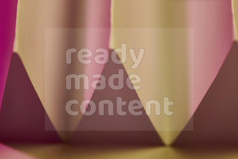 A close-up abstract image showing sharp geometric paper folds in pink gradients and warm tones