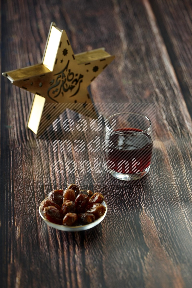 A wooden golden star lantern with different drinks, dates, nuts, prayer beads and quran on brown wooden background