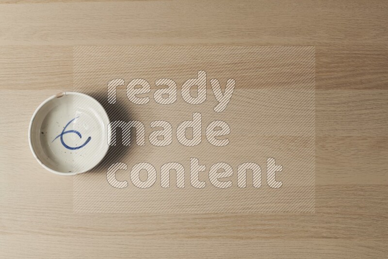 وعاء فخاري متعدد الألوان على خلفية خشبية فاتحة