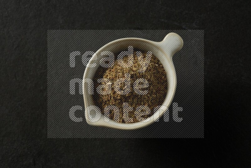 white ceramic round sauce bowl filled with herbs on grey textured countertop