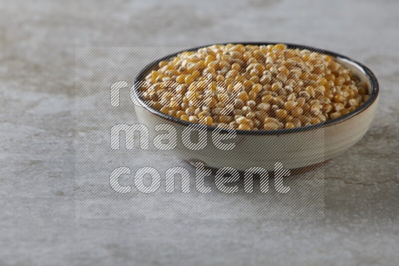 corn kernel in a multi-colored pottery bowl on a grey textured countertop