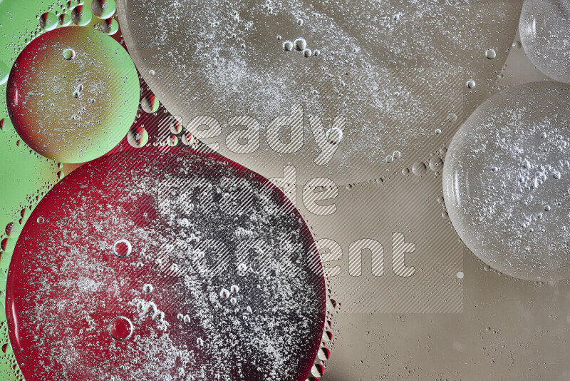 لقطات مقربة لفقاعات من الزيت على سطح الماء باللون البني والأخضر والأحمر