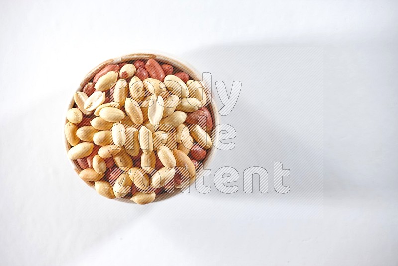 A beige ceramic bowl full of peeled peanuts on a white background in different angles