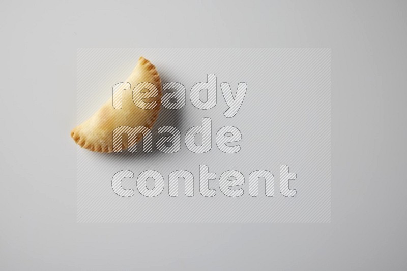 One fried sambosa from a top angle on a white background