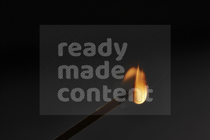 A burning matchstick isolated on dark backdrop