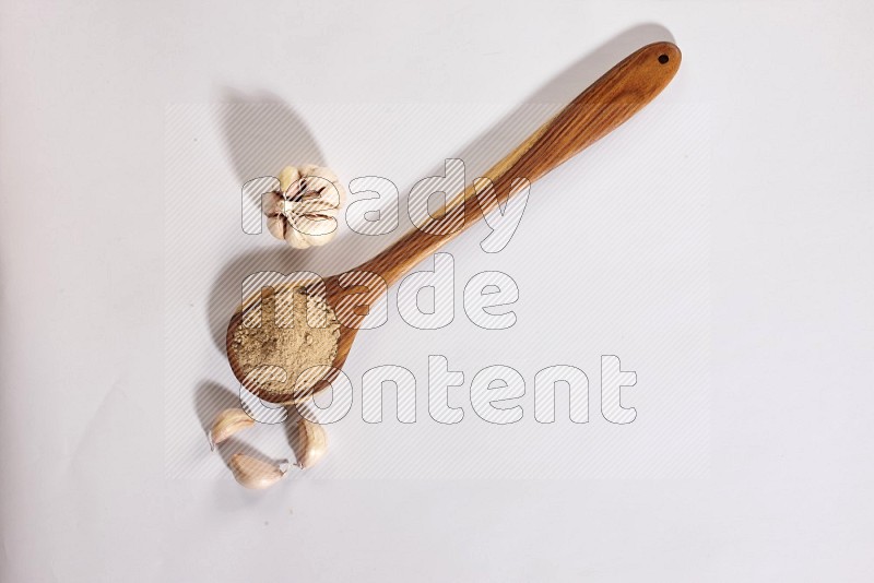 A wooden ladle full of garlic powder and beside it garlic bulb and cloves on a white flooring in different angles