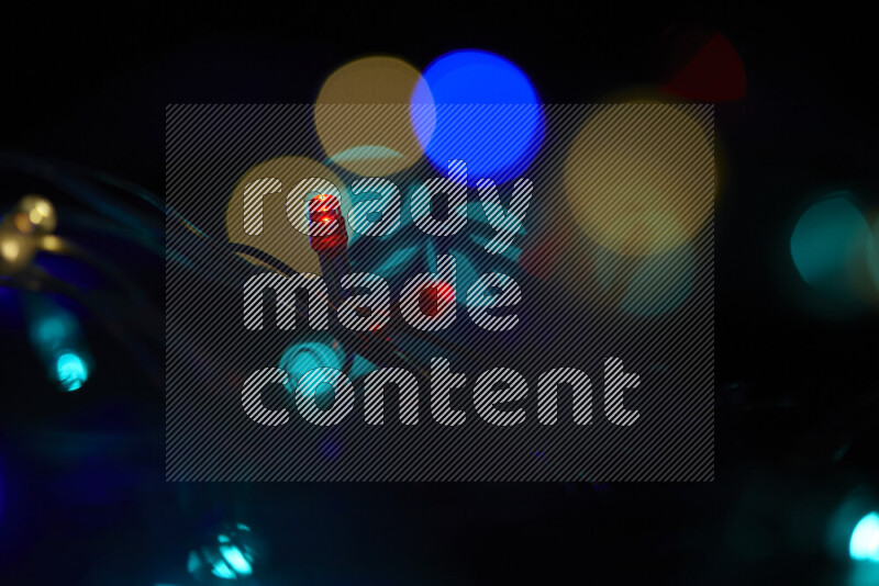 Light bulbs glowing against backdrop of multicolord bokeh