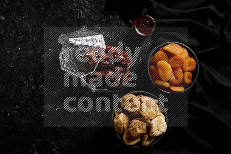 Dates in glass bowl with coffee and dried fruits in a dark setup