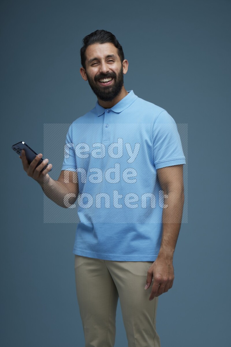 Man posing with a phone in a blue background wearing a Blue shirt
