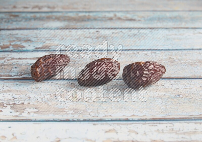 three madjoul dates on a light blue wooden background