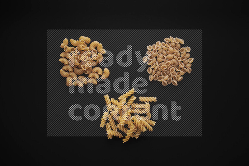 Different pasta types in bunches on black background