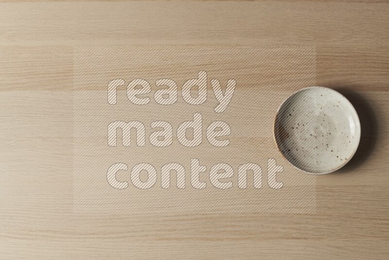 صحن فخاري متعدد الألوان على خلفية خشبية فاتحة