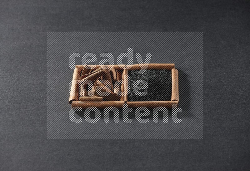 2 squares of cinnamon sticks full of black seeds and cinnamon on black flooring