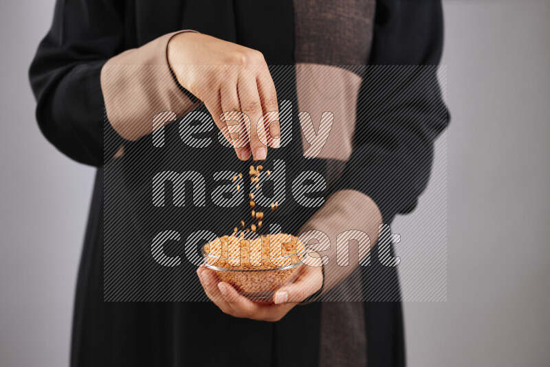 Woman in abaya holding different kinds of legumes in different positions