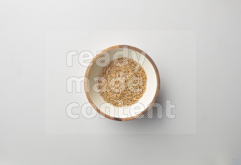 Top-view shot of long grain brown rice in a container on white background