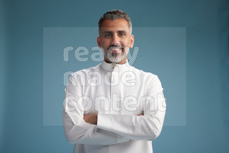 Saudi man waring thob posing to the camera on blue background