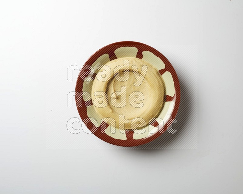Plain hummus in a traditional plate on a white background