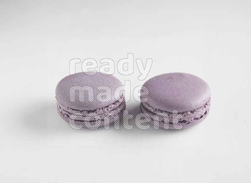 45º Shot of two Purple Blueberry macarons on white background