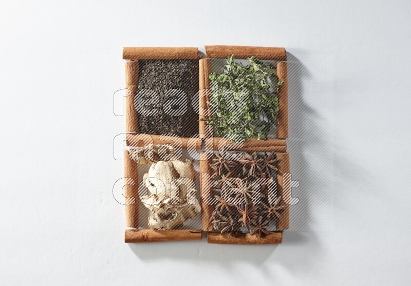 4 مربعات من أعواد القرفة ممتلئة بالشاي والنعناع واليانسون والزنجبيل على أرضية بيضاء