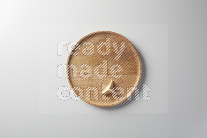 A single Sambosa on a wooden round plate on a white background