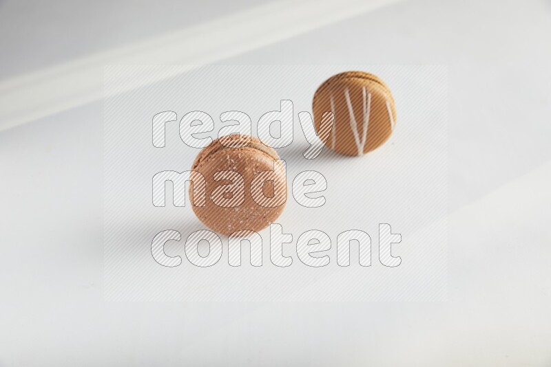 45º Shot of of two assorted Brown Irish Cream, and Brown Hazelnuts macarons on white background