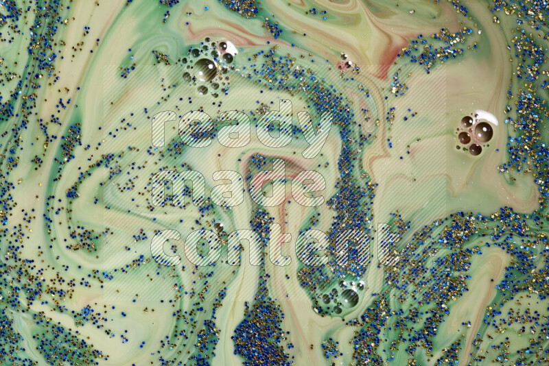 لقطة مقربة لبريق أزرق وذهبي متلألئ منتشر على خلفية من اللون الأخضر والأحمر في حركات دائرية