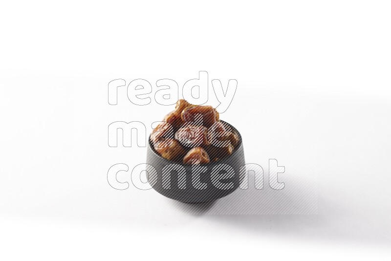 Dates in a black pottery bowl on white background