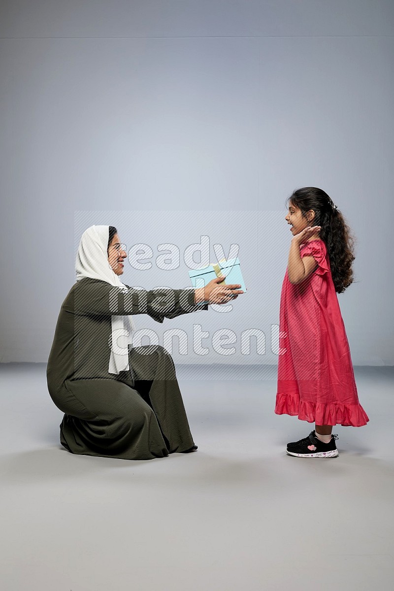 A girl giving a gift to her mother on gray background