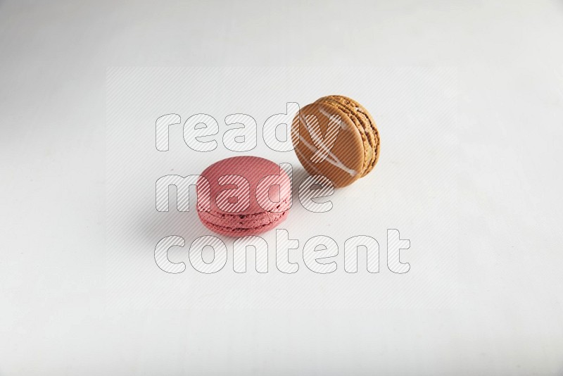 45º Shot of of two assorted Brown Irish Cream, and Pink Raspberry macarons on white background