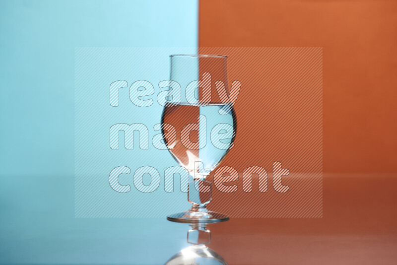 The image features a clear glassware filled with water, set against light blue and dark orange background