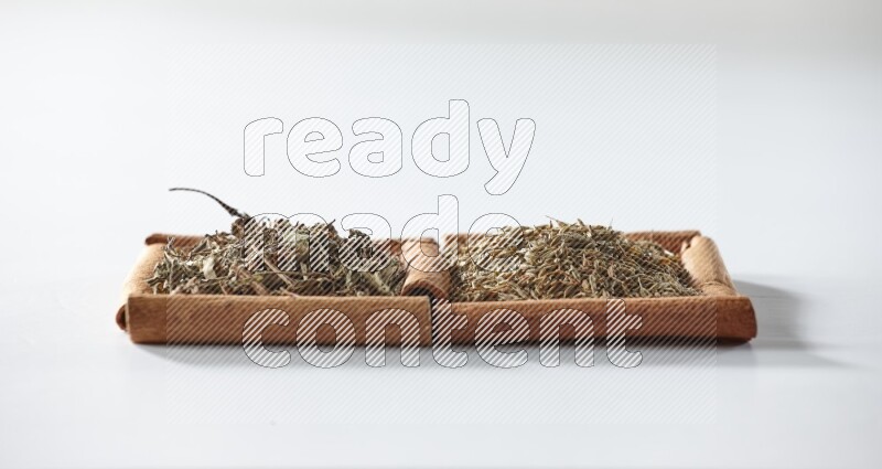 مربعان من أعواد القرفة ممتلئان بالريحان المجفف والكمون علي خلفية بيضاء