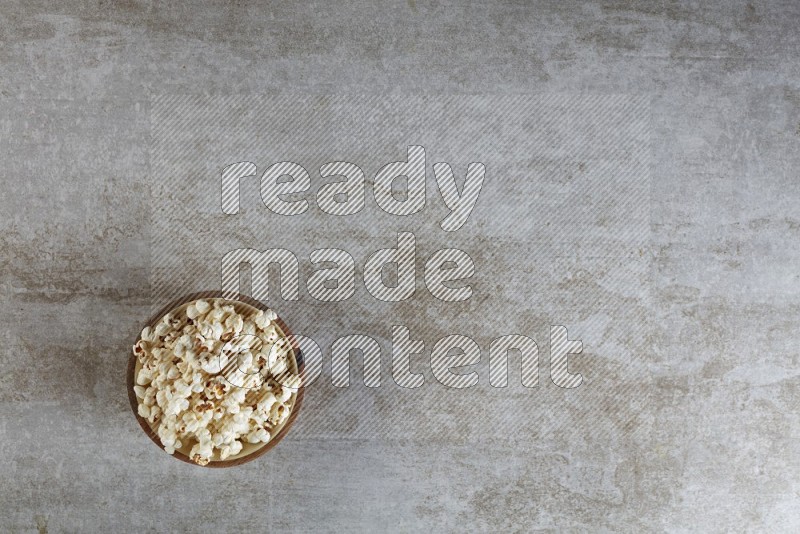 popcorn in wooden bowl on a grey textured countertop