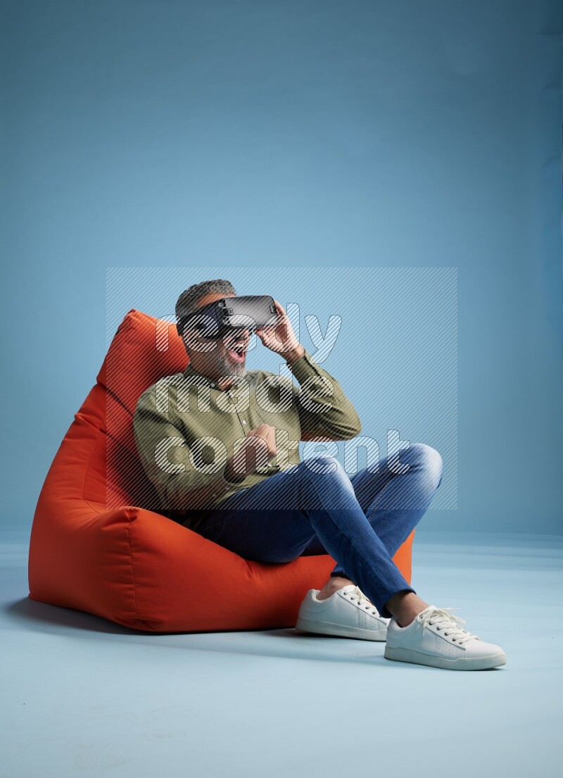 A man sitting on an orange beanbag and gaming with VR