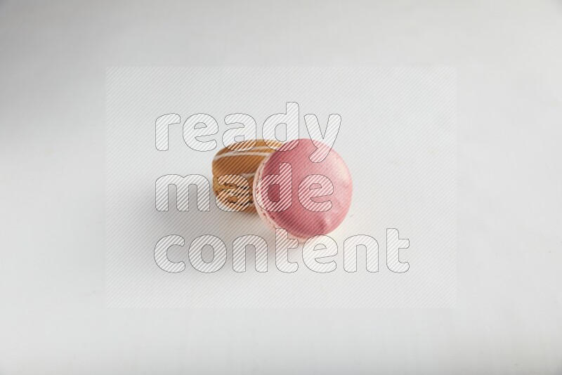 45º Shot of of two assorted Brown Irish Cream, and Pink Litchi Raspberry macarons on white background