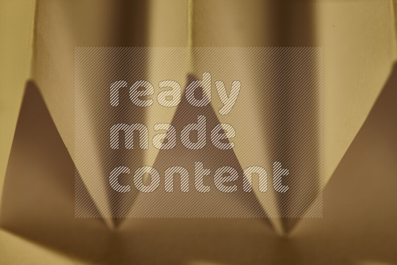 A close-up abstract image showing sharp geometric paper folds in warm gradients