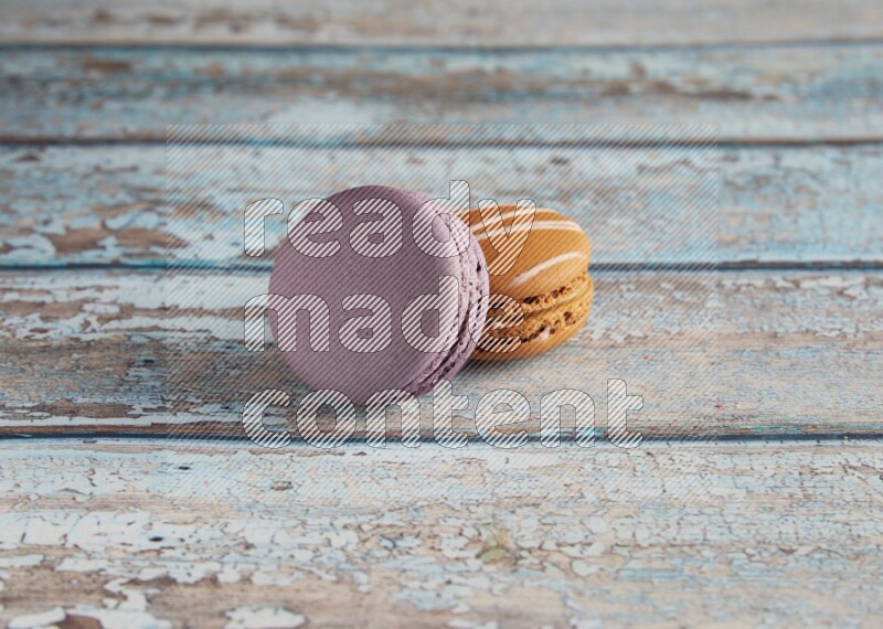 45º Shot of of two assorted Brown Irish Cream, and Purple Blueberry macarons  on light blue background