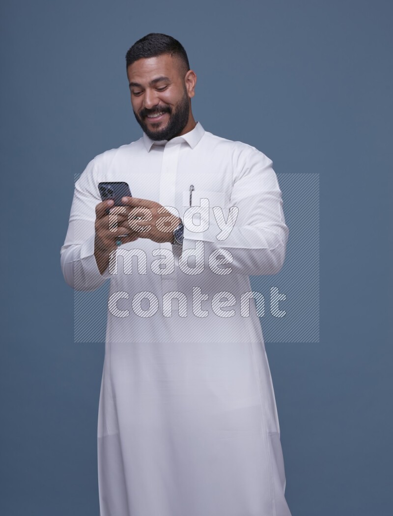A man Texting on Blue Background wearing Saudi Thob