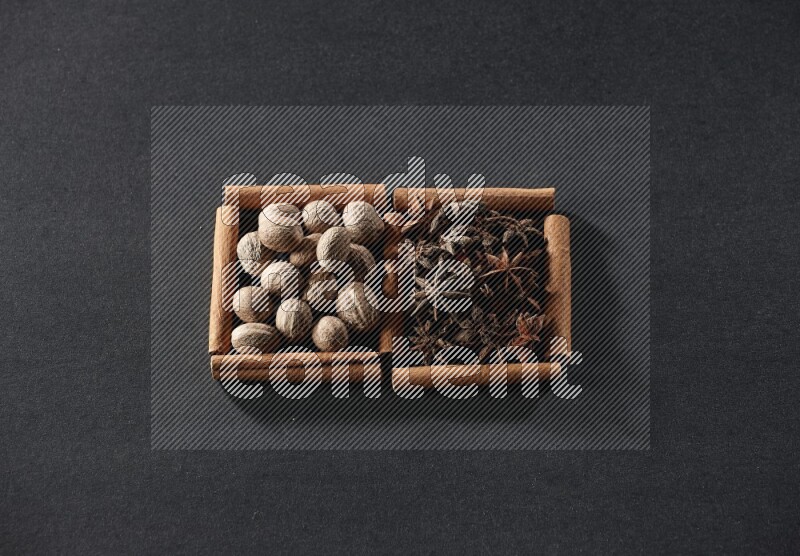 2 squares of cinnamon sticks full of nutmeg and star anise on black flooring