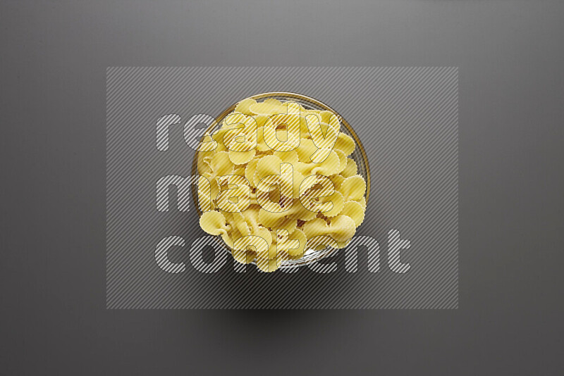 Fiocchi pasta in a glass bowl on grey background