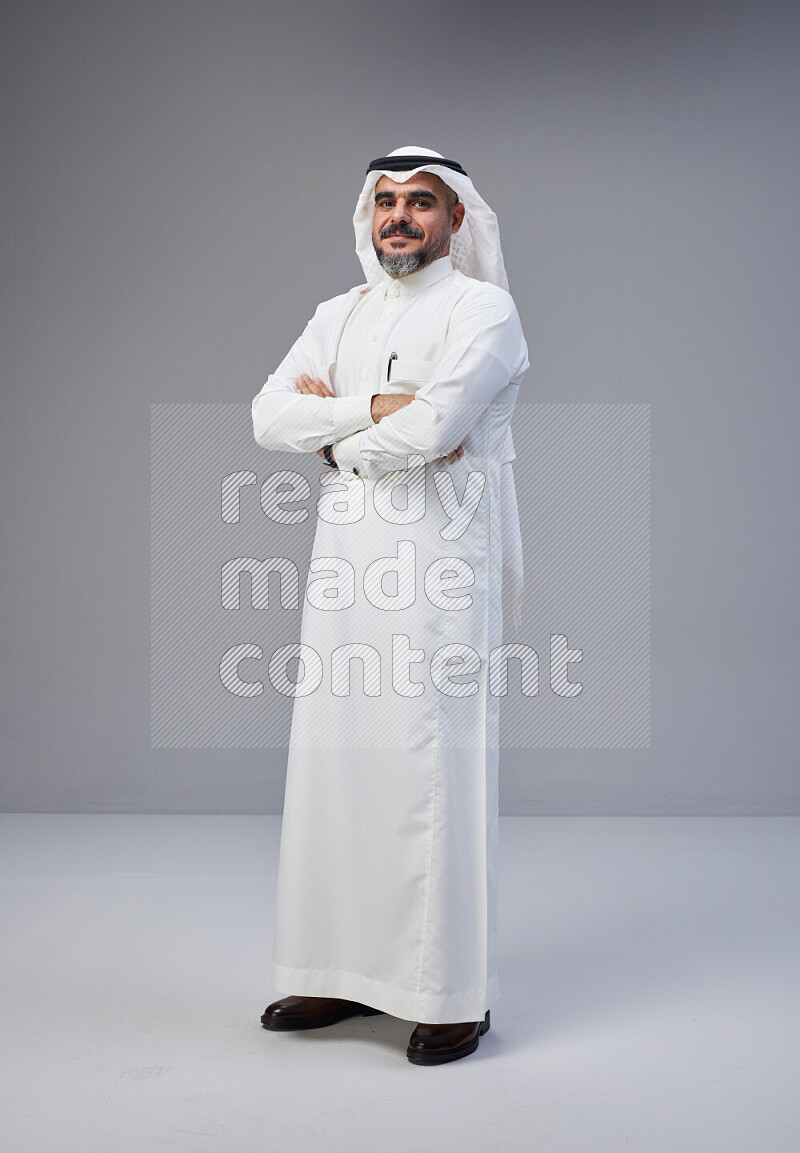 Saudi man Wearing Thob and white Shomag standing with crossed arms on Gray background