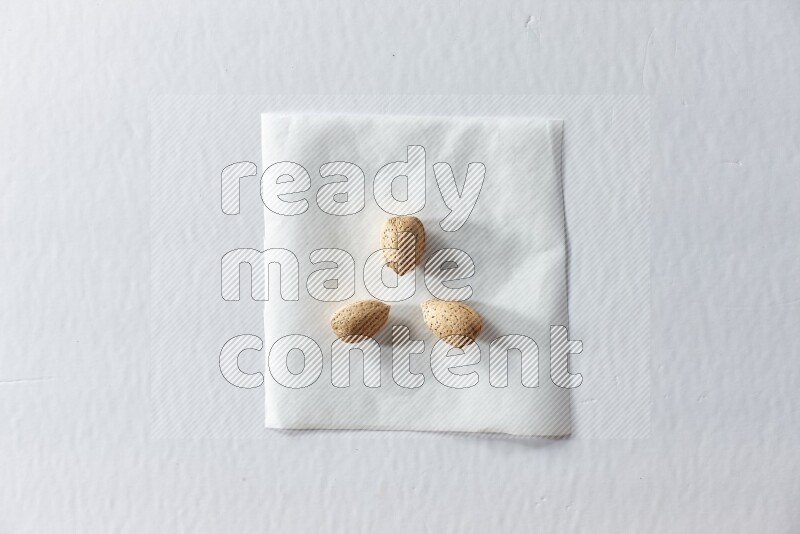 3 almonds on a piece of paper on a white background in different angles