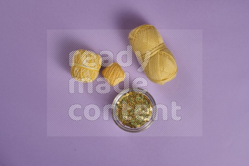 A yellow and purple collection of sewing and tailoring tools arranged on a purple background
